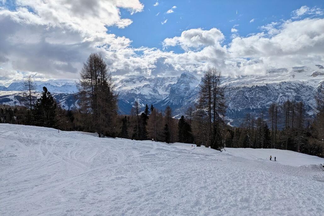 Blick von der Heiligkreuzkirche. Hinten in der Mitte der Sellastock. Gran Risa versteckt sich weiter links hinter Bäumen (man sieht einen Teil der roten Gran Risa).