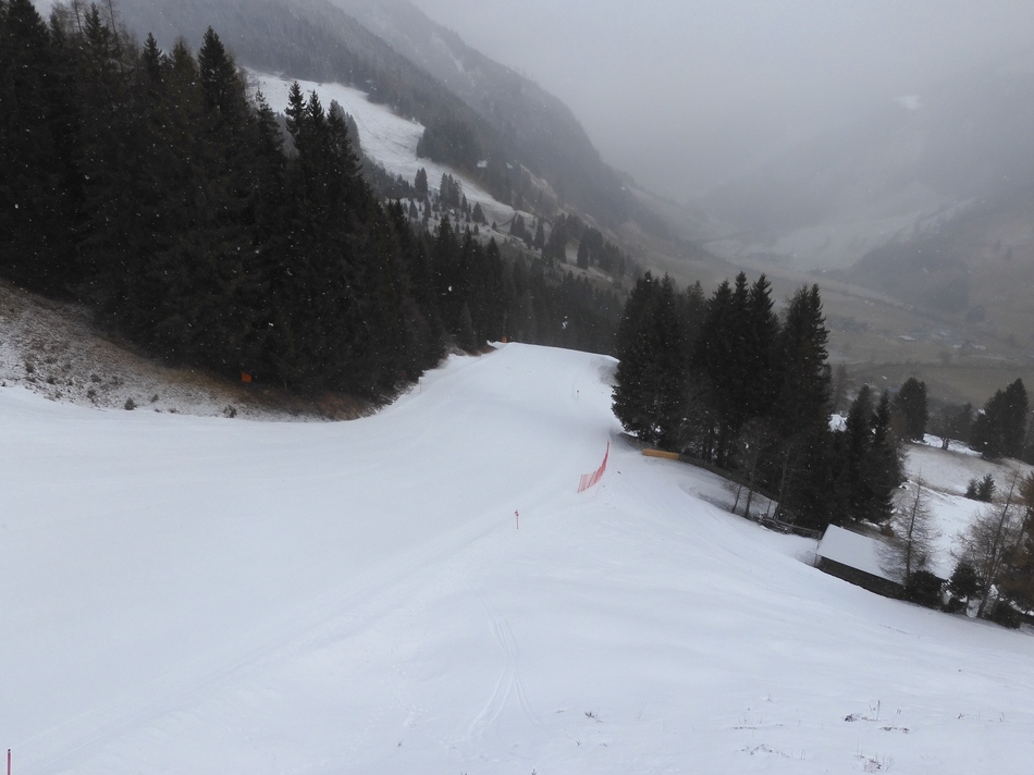 Blick aus dem Sessellift auf die Talabfahrt. Es schneit leicht.