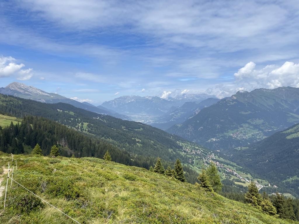 Blick auf Malix. Im Hintergrund ist das Rheintal zu sehen. Der Rhein und weiter hinten Landquart sind zu erahnen.