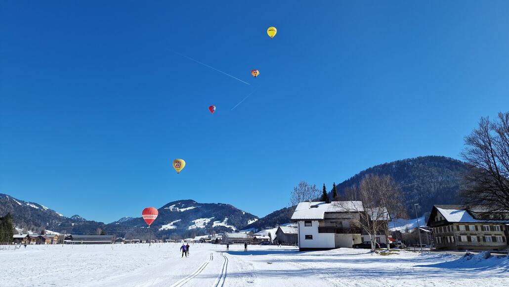 Heissluftballons gleiten durch den winterlichen Bregenzerwald.