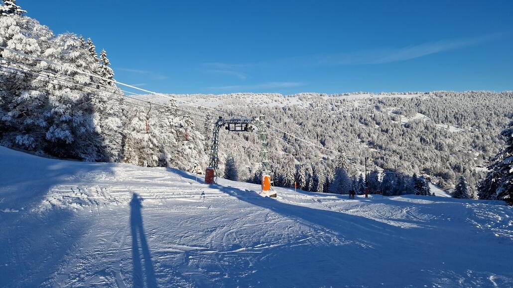 Ein malerischer Blick auf den Skilift und die verschneite Landschaft. Im Hintergrund erhebt sich der nördliche Bergrücken des Chasseral.