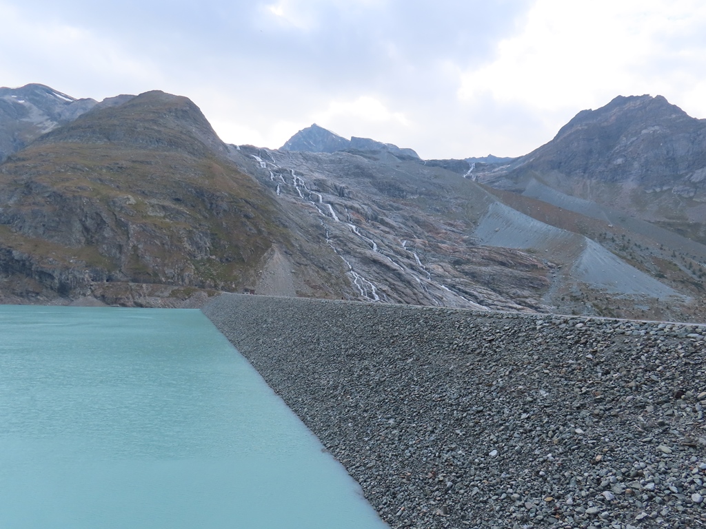 Staumauer und Bäche, die vom Allalingletscher durch das Gelände führen, aus dem sich der Gletscher zurückgezogen hat.