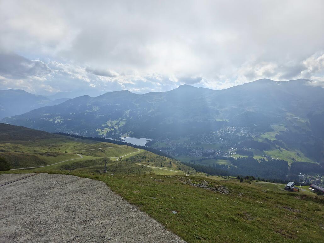 Etwas oberhalb vom Heimberg komme ich wieder aus dem Nebel raus. So wird nun der Blick auf die Lenzerheide mit dem Heidsee sowie die gegenüberliegende Bergkette zwischen Stätzerhorn und Piz Scalottas frei.