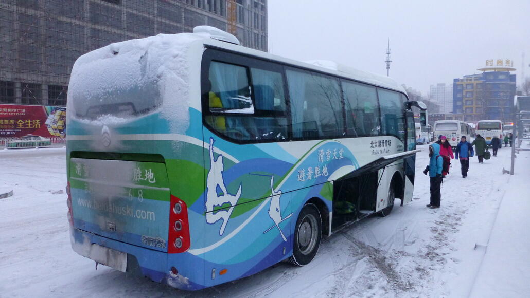 Anreise mit dem offiziellen Skibus vom Zentrum der Stadt Jilin, hier in China eine Kleinstadt mit knapp 4 Mio. Einwohnern, die im Westen kaum jemand kennt. Weiss nicht mehr, ob meine Frau den Platz im Bus auf einer chinesischen Webseite reservieren musste oder ob wir einfach zur Abfahrt dort aufkreuzten. Ein paar Jilin-Locals mussten uns aber helfen, den Halteort des Buses überhaupt erst mal zu finden, das weiss ich noch, da das gesamte Stadtzentrum gerade neu gebaut wurde, so ca. 500 m x 500 m Baustelle einfach komplett abgesperrt. ;)